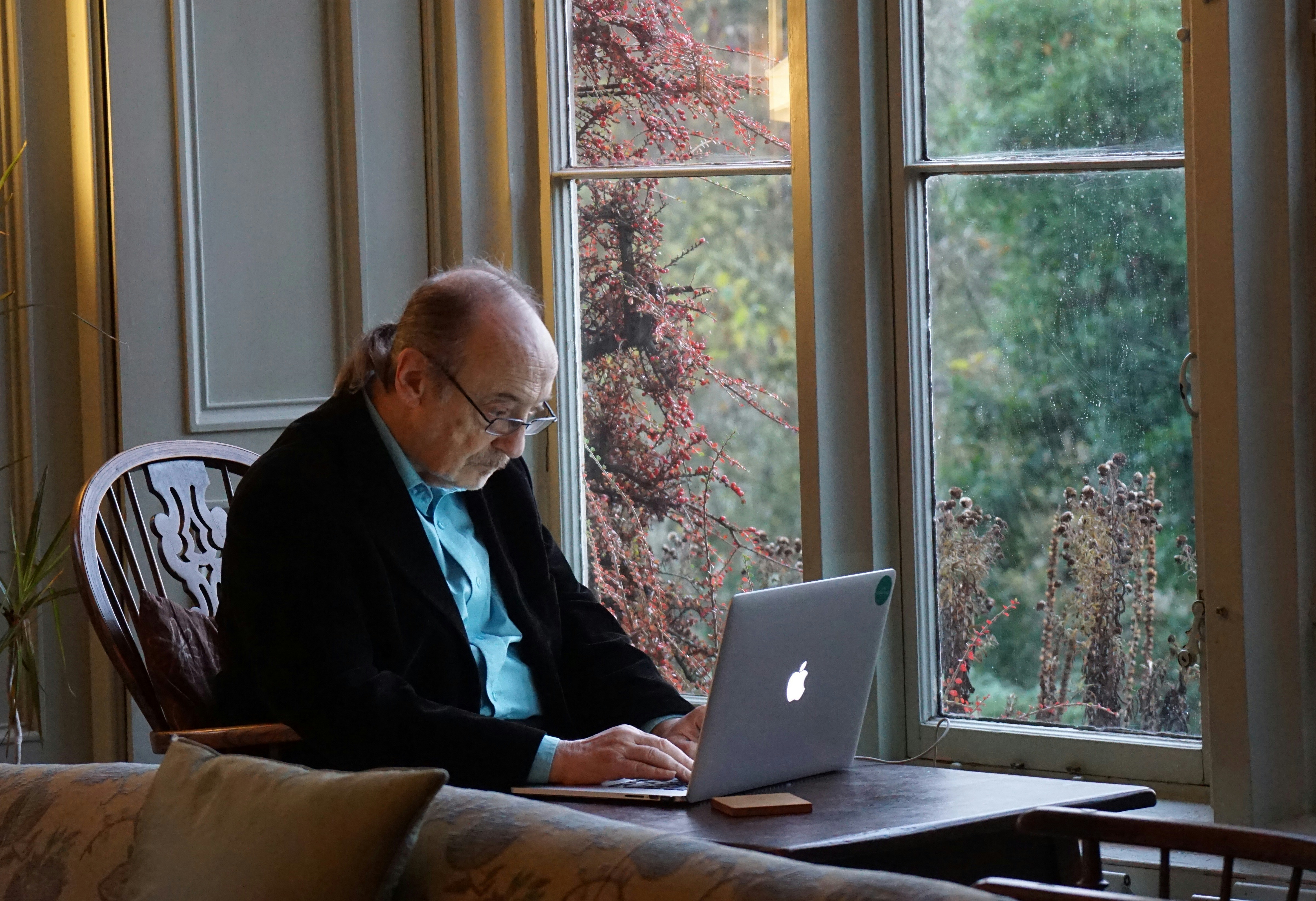 Elderly resident sitting at a table working on a laptop